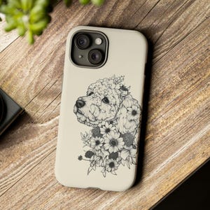 Könnte beinhalten: Eine weiße Handyhülle mit einer Schwarzweißillustration eines Pudels mit Blumen um den Kopf.