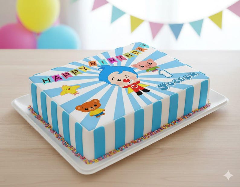 May include: A rectangular birthday cake with blue and white stripes, decorated with cartoon characters and the words "HAPPY BIRTHDAY" and "Joseph". The cake sits on a white tray and is decorated with colorful sprinkles.