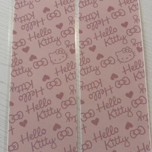 May include: Two pink Hello Kitty patterned cards. The cards feature a repeating pattern of Hello Kitty faces, bows, and hearts. The text "Hello Kitty" is also repeated throughout the design.