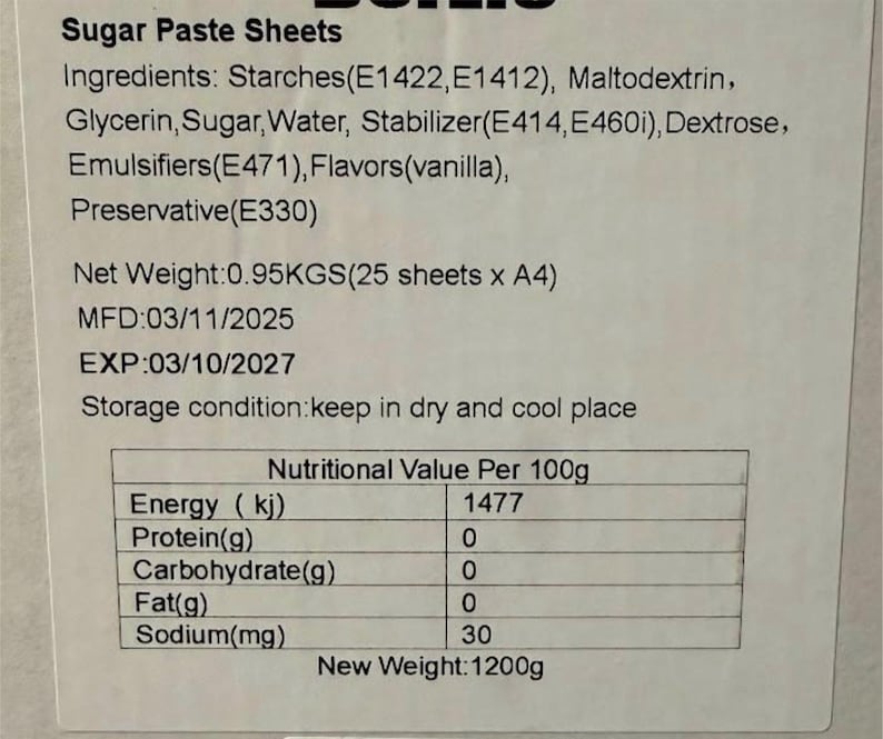 May include: A close-up of a label for sugar paste sheets. The label lists ingredients, net weight, manufacturing and expiration dates, storage conditions, and nutritional information per 100g. The new weight is 1200g.