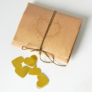 Wedding anniversary gift wrapping. Origami envelope with gold heart shaped confetti inside.