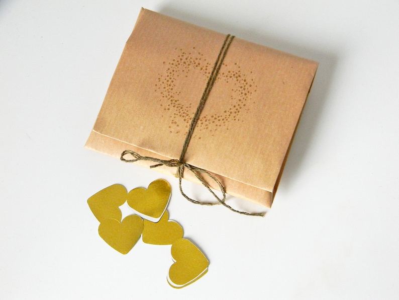 Wedding anniversary gift wrapping. Origami envelope with gold heart shaped confetti inside.