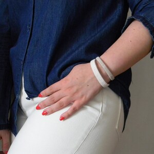 Woman wearing two cuff bracelets on her wrist. Wool and metal bracelets for the seventh wedding anniversary, the wool anniversary.
