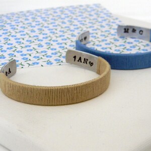 Cuff bracelets. Metal and cotton thread. Wrapped with cotton thread in two different colors. Beige and azure. Inner engraving with initials and 1 year in french. In France the cotton anniversary is for the 1st wedding anniversary. They are personalizable in color and engraving.