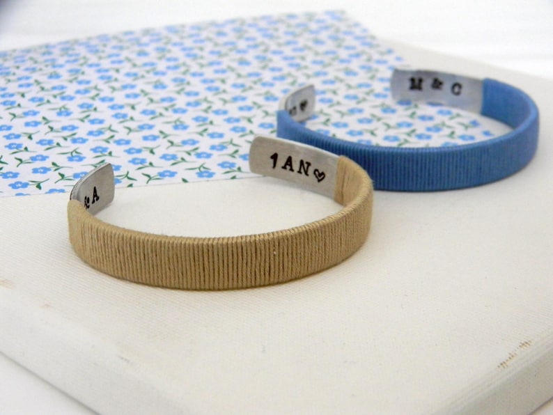 Cuff bracelets. Metal and cotton thread. Wrapped with cotton thread in two different colors. Beige and azure. Inner engraving with initials and 1 year in french. In France the cotton anniversary is for the 1st wedding anniversary. They are personalizable in color and engraving.