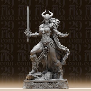 May include: A detailed gray sculpture of a female warrior, holding a sword aloft. She wears a horned helmet, fur accents, and armor. The figure stands on a decorative base with intricate carvings, showcasing a dynamic pose.