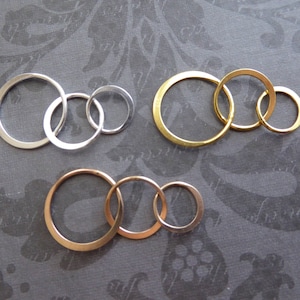 May include: Three sets of interlocking metal rings. The first set is silver, the second is gold, and the third is a mix of silver and gold.