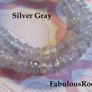 May include: A strand of silver gray faceted gemstone beads. The beads are small and round, and they have a smooth, polished finish. The beads are strung on a clear thread. The text "Silver Gray" and "FabulousRocks" is visible in the image.