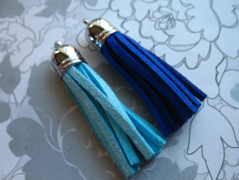 May include: Two leather tassels with silver metal tops. One tassel is blue and the other is light blue.
