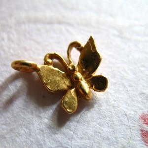 Puede incluir: Un dije de mariposa de color dorado con un bucle para sujetarlo a un collar o pulsera.