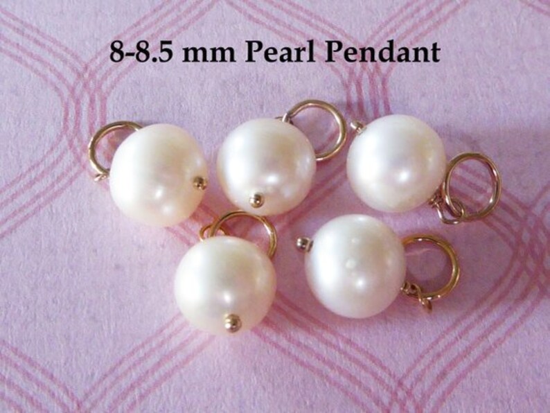 May include: Six white pearl pendants with gold jump rings. The pearls are 8-8.5 mm in size.