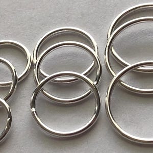 May include: A set of silver jump rings in various sizes. The rings are smooth and shiny, and they are perfect for jewelry making or other crafting projects.
