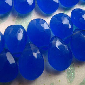Pu&ograve; includere: Una collana di perline di pietra preziosa blu brillante, ogni perla &egrave; sfaccettata e a forma di lacrima. Le perline sono infilate su un filo trasparente.