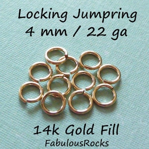 May include: A close-up of 14k gold filled jump rings, 4 mm in size and 22 gauge. The rings are arranged in a loose pile on a light blue surface. The text "Locking Jumpring 4 mm / 22 ga" and "14k Gold Fill FabulousRocks" is visible in the image.