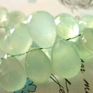 Puede incluir: Una hebra de cuentas de piedras preciosas de color verde claro, cada cuenta est&aacute; facetada y tiene forma de l&aacute;grima. Las cuentas est&aacute;n enhebradas en un hilo transparente.