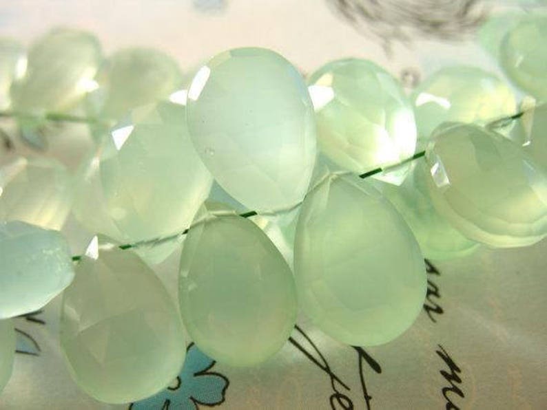 Puede incluir: Una hebra de cuentas de piedras preciosas de color verde claro, cada cuenta est&aacute; facetada y tiene forma de l&aacute;grima. Las cuentas est&aacute;n enhebradas en un hilo transparente.
