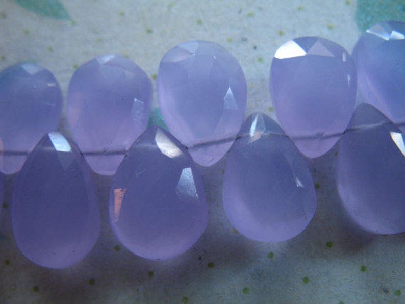Puede incluir: Una hebra de cuentas de piedras preciosas de color p&uacute;rpura claro, cada cuenta est&aacute; facetada y tiene forma de l&aacute;grima.
