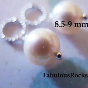 May include: Two white pearl beads with silver jump rings, measuring 8.5-9 mm in diameter.