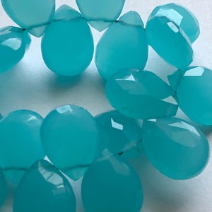 Pu&ograve; includere: Una collana di perle di pietra preziosa blu turchese a forma di goccia. Le perle sono infilate su un filo sottile.