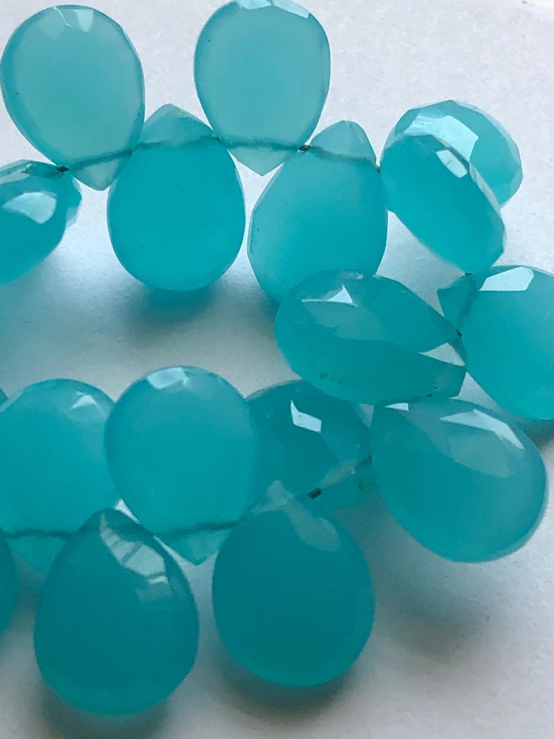 Pu&ograve; includere: Una collana di perle di pietra preziosa blu turchese a forma di goccia. Le perle sono infilate su un filo sottile.