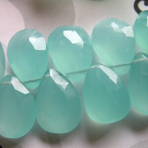 Pu&ograve; includere: Una collana di perle di pietra preziosa di forma a goccia di colore blu chiaro. Le perle sono lisce e lucidate, con un aspetto traslucido.