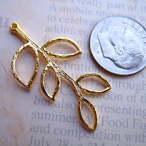 May include: Gold-toned metal leaf charm with five leaves and a loop at the top. The charm is about the size of a US dime.