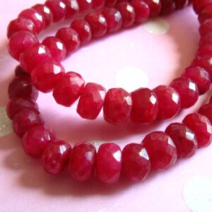 Puede incluir: Una hebra de cuentas de piedras preciosas facetadas de color rojo intenso. Las cuentas son redondas y tienen un acabado pulido.