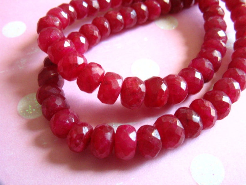 Puede incluir: Una hebra de cuentas de piedras preciosas facetadas de color rojo intenso. Las cuentas son redondas y tienen un acabado pulido.