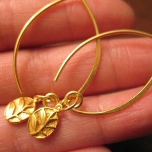 Puede incluir: Pendientes de oro con un delicado dise&ntilde;o de hojas. Los pendientes est&aacute;n hechos de alambre fino y tienen un estilo simple y elegante.
