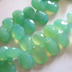 Puede incluir: Una hebra de cuentas de piedras preciosas de color verde claro, cada cuenta est&aacute; facetada y tiene forma de l&aacute;grima.