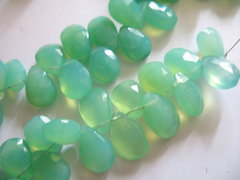 Puede incluir: Una hebra de cuentas de piedras preciosas de color verde claro, cada cuenta est&aacute; facetada y tiene forma de l&aacute;grima.