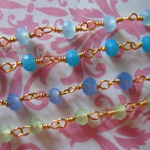 May include: Four strands of a delicate gold chain necklace with light blue and green gemstone beads.