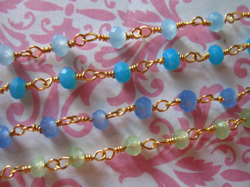 May include: Four strands of a delicate gold chain necklace with light blue and green gemstone beads.