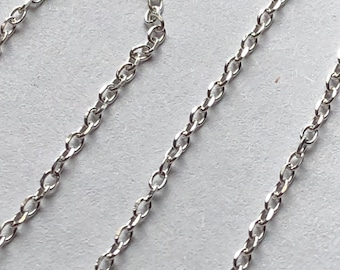 May include: A silver chain necklace with a delicate, cable chain design. The chain is made of small, linked oval shapes.