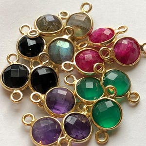 May include: Assortment of gemstone beads with gold-toned connectors. The beads are in various colors, including black, green, purple, pink, and gray.