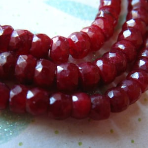 Puede incluir: Una hebra de cuentas de piedras preciosas facetadas de color rojo intenso. Las cuentas son redondas y tienen un acabado liso y pulido.