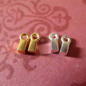 May include: Four metal jump rings, two gold and two silver, with a square shape and a small loop at the top.