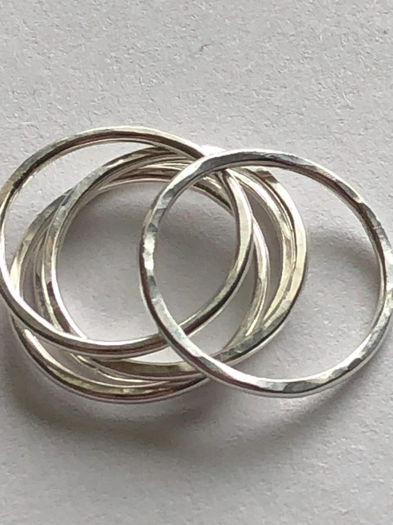 May include: A set of six silver hammered stacking rings. The rings are thin and delicate, and they are arranged in a stack.