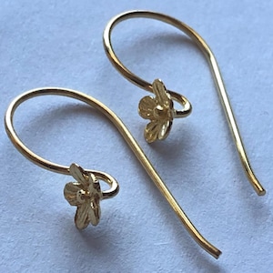 May include: A pair of gold flower-shaped dangle earrings with a simple hook design.