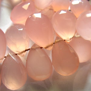 Puede incluir: Una hebra de cuentas de piedras preciosas rosas, cada cuenta est&aacute; facetada y tiene forma de l&aacute;grima. Las cuentas est&aacute;n enhebradas en un alambre fino.