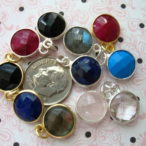 May include: Assortment of round gemstone pendants with silver and gold accents. The gemstones are black, red, blue, gray, and clear.