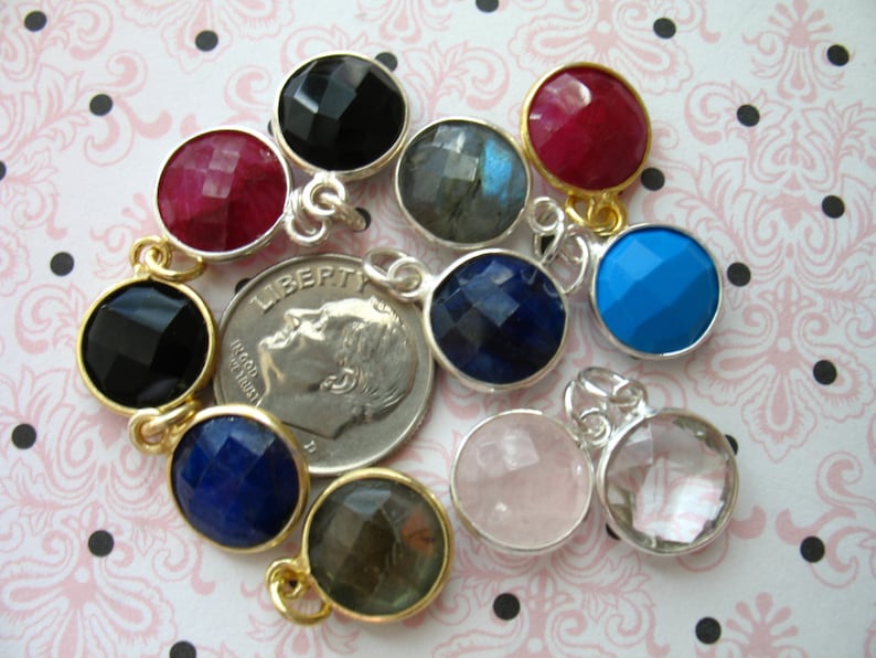 May include: Assortment of round gemstone pendants with silver and gold accents. The gemstones are black, red, blue, gray, and clear.