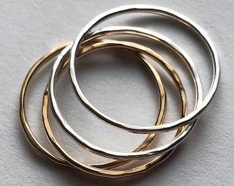 May include: Four simple stacking rings, two gold and two silver, with a hammered finish.