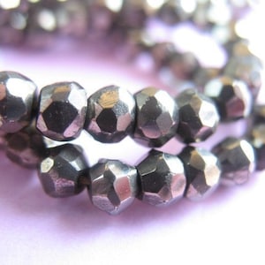 May include: A strand of silver-toned faceted beads. The beads are small and have a geometric shape.