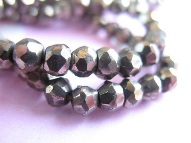 May include: A strand of silver-toned faceted beads. The beads are small and have a geometric shape.