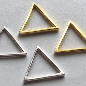 May include: Four triangle-shaped metal jump rings. Two are silver and two are gold.