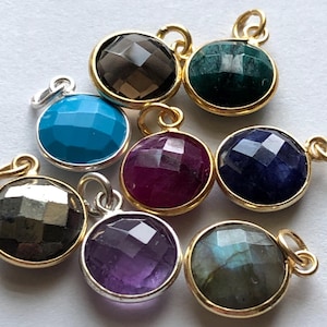 May include: Assortment of eight gemstone pendants with gold and silver settings. The gemstones are amethyst, turquoise, ruby, labradorite, smoky quartz, sapphire, emerald, and pyrite.