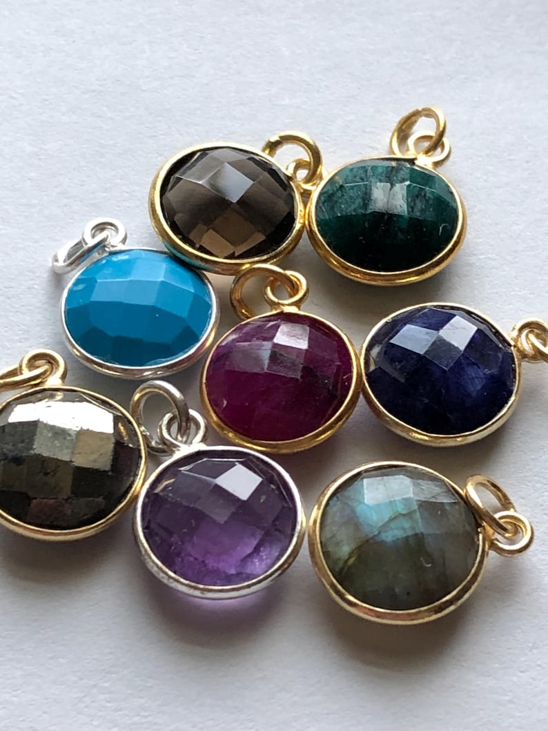 May include: Assortment of eight gemstone pendants with gold and silver settings. The gemstones are amethyst, turquoise, ruby, labradorite, smoky quartz, sapphire, emerald, and pyrite.