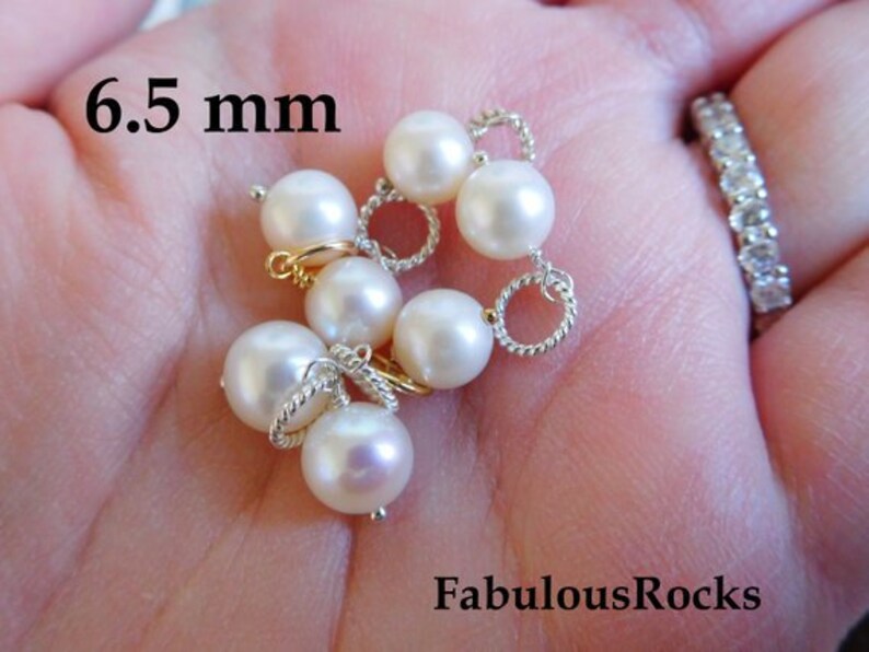 May include: A close-up of a strand of white pearls with silver and gold accents. The pearls are 6.5 mm in diameter.