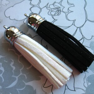 May include: Two tassels, one black and one white, with silver metal tops. The tassels are made of a soft, fuzzy material.